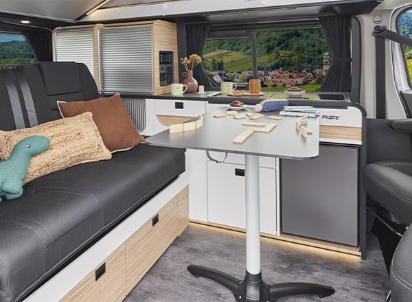 Vue intérieure avec table dans le salon d'un van aménagé Pilote